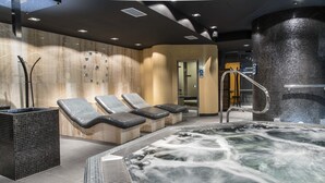 A modern spa area with a hot tub, lounge chairs, and a tiled wall. - Domaša Zelená Lagúna (Kvakovce)
