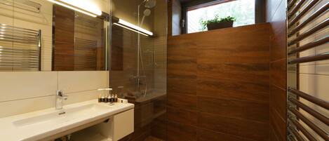 A modern bathroom with a glass-enclosed shower, a white sink, and a wooden vanity.