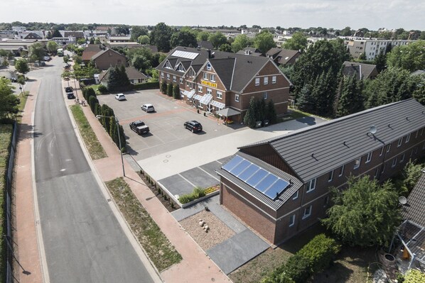 Un hotel con estacionamiento, paneles solares en el techo y un edificio grande con muchas ventanas.