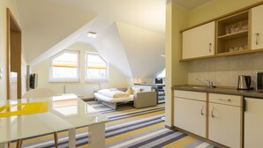 A modern kitchen with a dining area, a small bedroom, and a view of the outside. - Hotel Globotel Business (Garbsen)