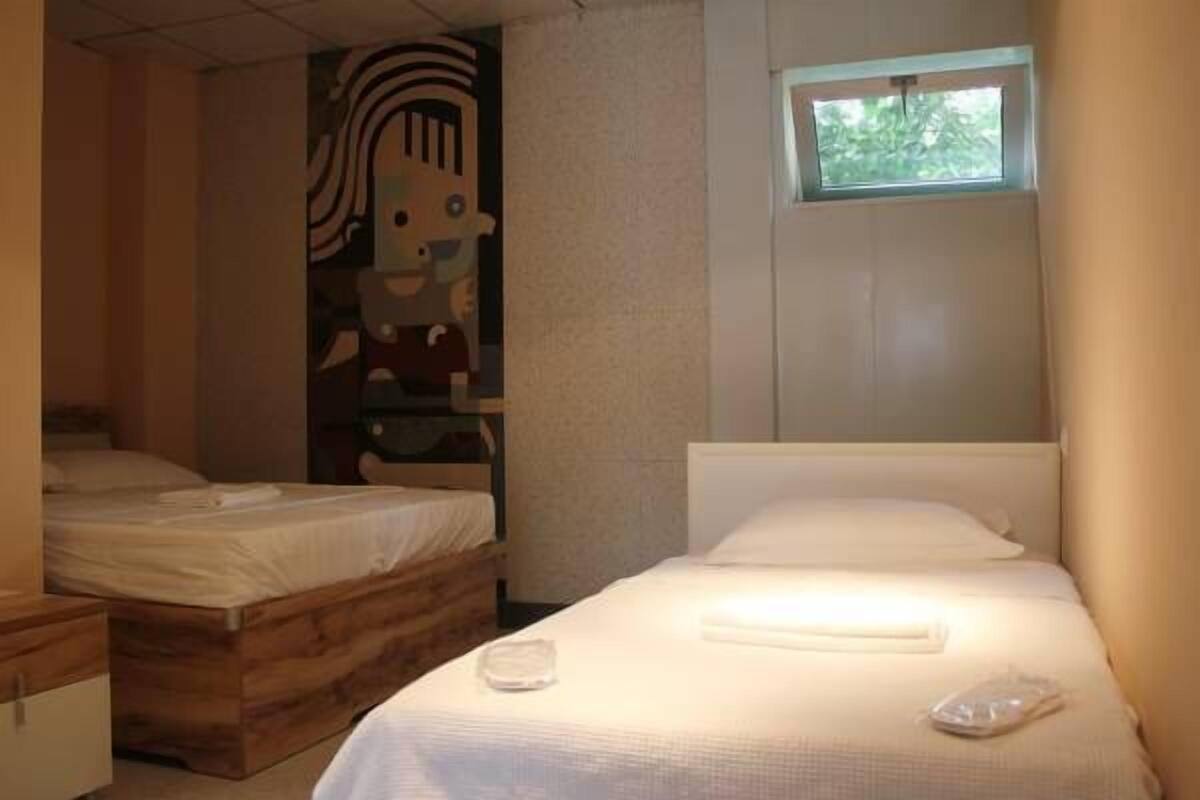 A bedroom with two beds, a window, and a wall mural.