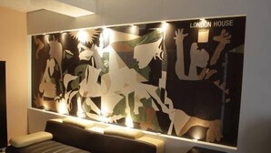 A modern living room with a large abstract artwork on the wall, a sofa, and a small table. - London Palace (Tbilisi)