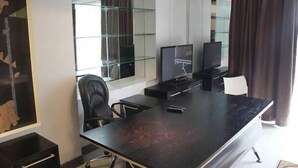 A modern office space with a large conference table, two black office chairs, a television, and a glass partition. - London Palace (Tbilisi)