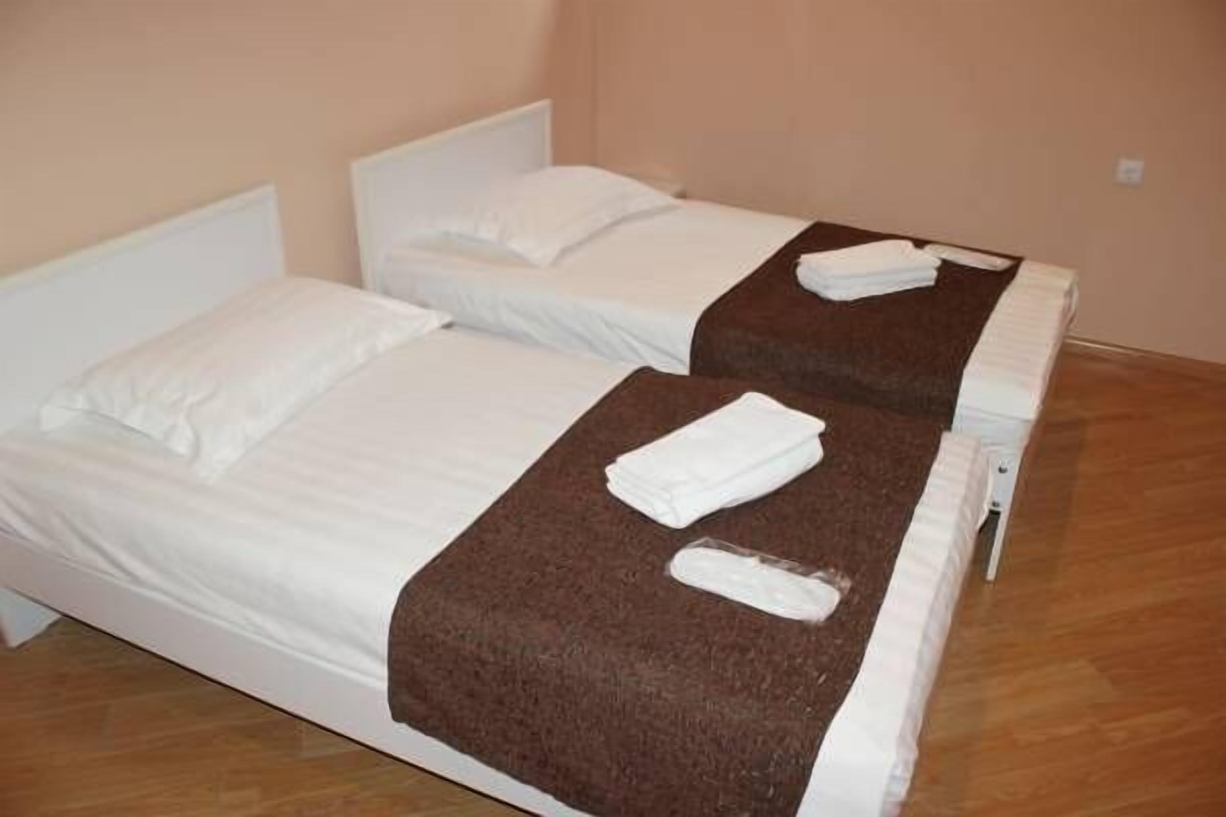 Two single beds with white linens and brown headboards, each with a folded white towel.