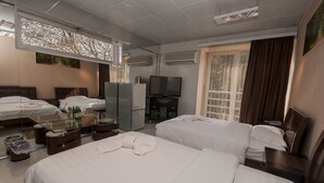 A hotel room with two beds, a TV, a minibar, and a large window with curtains. - London Palace (Tbilisi)