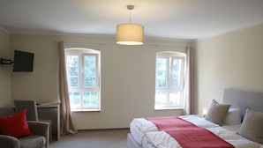 A hotel room with a bed, a desk, a chair, and two windows. - Obermühle Görlitz (Görlitz)