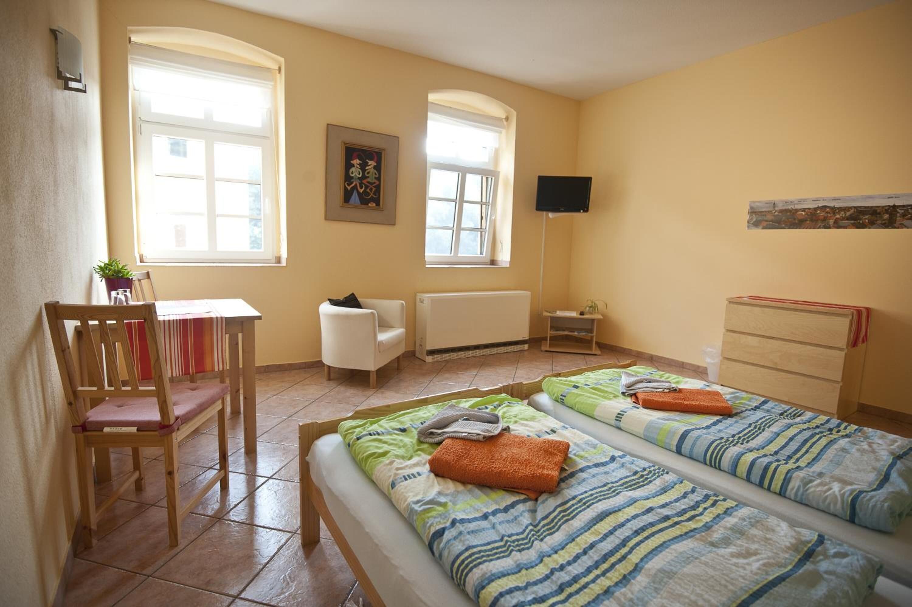 A room with two beds, a chair, a table, and a TV.