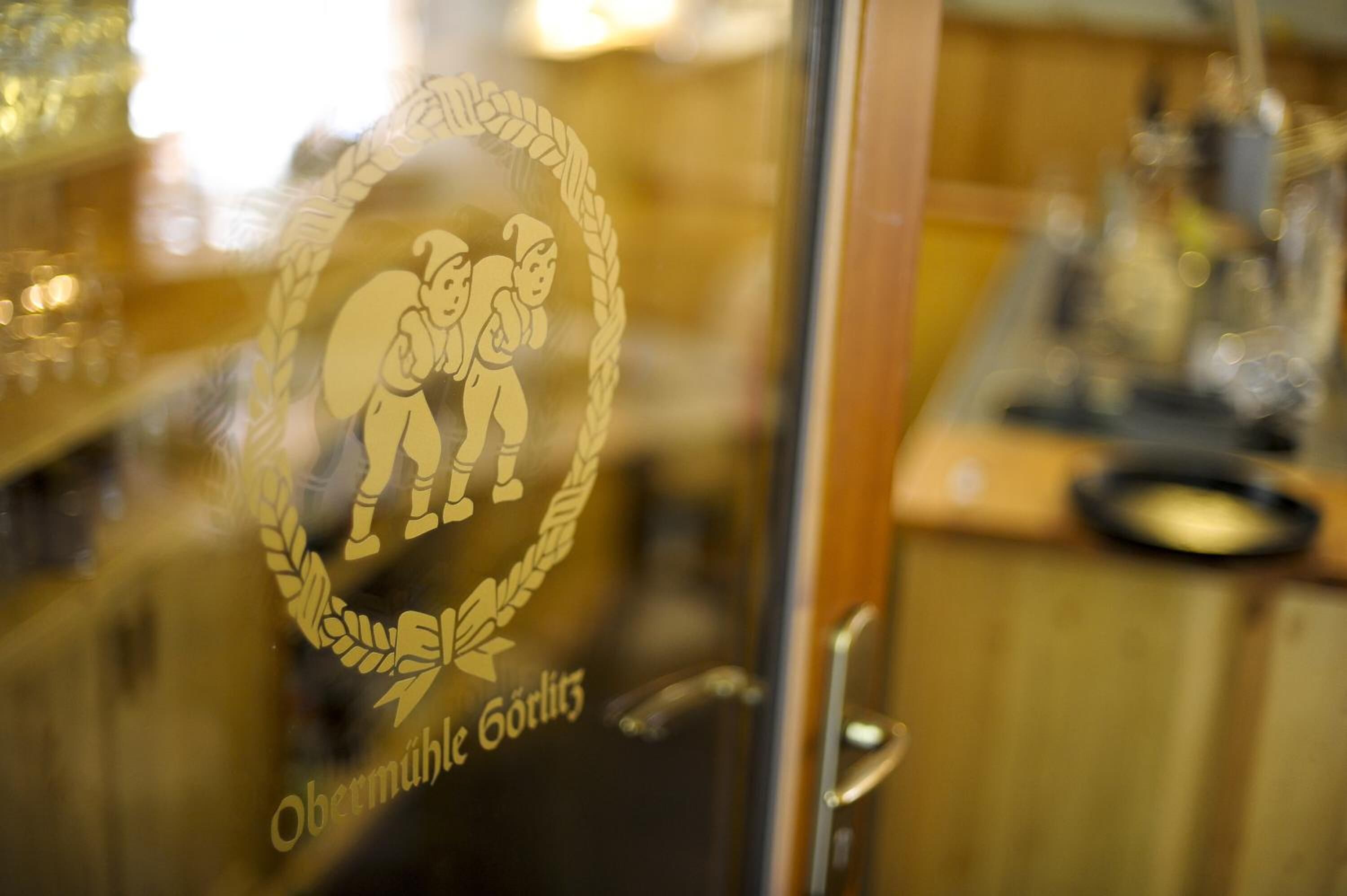 A glass door with a logo featuring two figures and the text "Obermühle Görlitz".