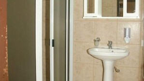 Un baño con inodoro, lavamanos y ducha con puertas de vidrio esmerilado.