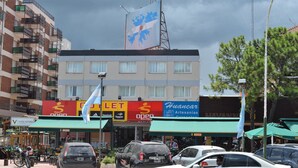 Un edificio de varios pisos con diversos comercios en la planta baja, incluyendo un hotel y una tienda de deportes.