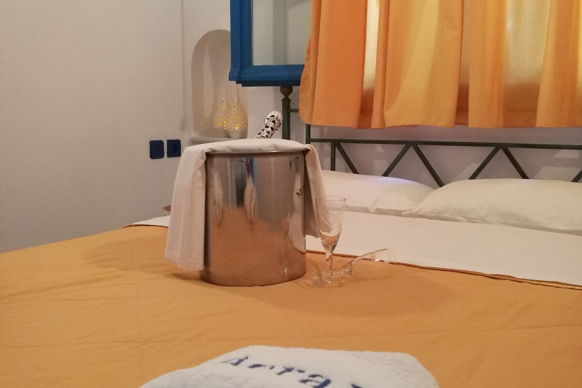 Une chambre d’hôtel avec un lit, une table de chevet, une lampe et une fenêtre avec des rideaux.