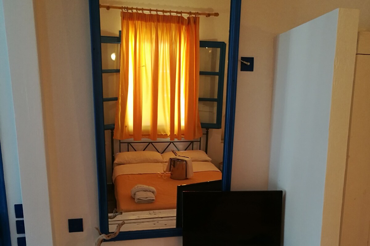 A bedroom with a bed, a television, and a mirror above the bed.