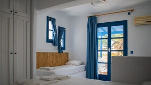 A hotel room with a bed, a wardrobe, a window with curtains, and a view of the outdoors. - Aeraki Studios & Apartments (Naxos)
