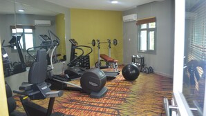 A gym with exercise equipment, a mirror, and a patterned carpet. - Lakewood Luxury Apartment (Abuja)