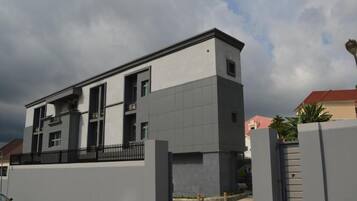 A modern two-story building with a grey facade and a black fence.