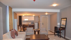 A compact living space with a sofa, two armchairs, a coffee table, a small kitchen area with a microwave, and a dining table. - Lakewood Luxury Apartment (Abuja)