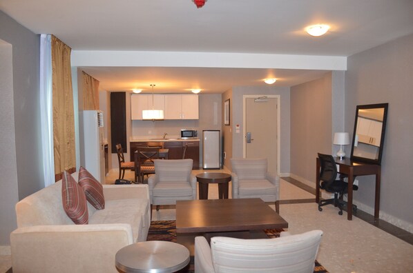 A compact living space with a sofa, two armchairs, a coffee table, a small kitchen area with a microwave, and a dining table.