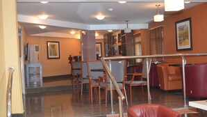 A lobby with a staircase, seating area, and a reception desk.