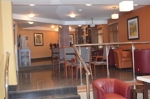 A lobby with a staircase, seating area, and a reception desk.