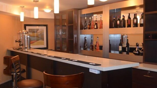 A bar area with a long counter, multiple seating options, and a wine display. - Lakewood Luxury Apartment (Abuja)