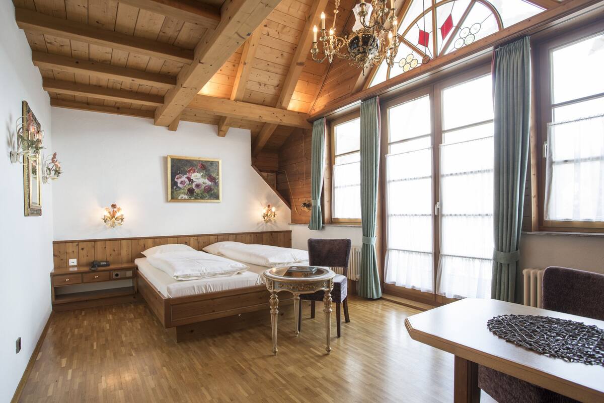 Habitación con piso de madera, una cama, una mesa y una silla.