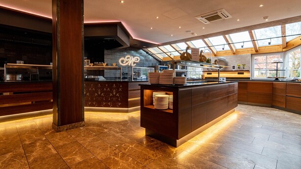 A modern kitchen with a central island, wooden cabinets, and a skylight. - Meiser Rosenstuben Hotel (Fichtenau)