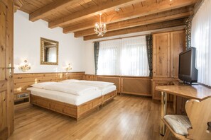 A wooden bedroom with a bed, a television, and a chair.