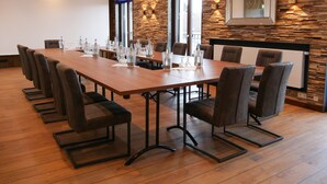 A conference room with a long table, chairs, and a wooden wall with a stone pattern. - Meiser Rosenstuben Hotel (Fichtenau)