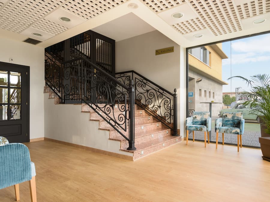 A staircase with ornate black railings, a wooden floor, and a view of the outside.