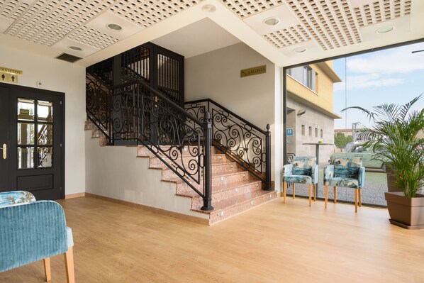 A staircase with ornate black railings, a wooden floor, and a view of the outside.