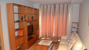 A living room with a wooden entertainment unit, a sofa, a coffee table, and a television. - Apartamentos Dos Torres Barbol (Zaragoza)