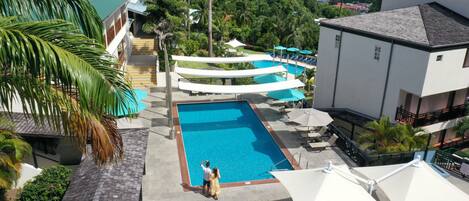 A resort with a swimming pool, outdoor seating, and a view of the ocean.