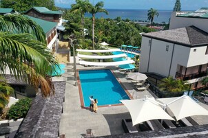 Un resort con piscina, mobiliario exterior y vista al océano.