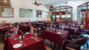 A restaurant with multiple tables set for dining, featuring red tablecloths and leather chairs. - Bel Jou Hotel – Adults Only – All Inclusive (Castries)