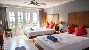 A hotel room with two beds, a desk, a chair, a phone, and a ceiling fan. - Bel Jou Hotel – Adults Only – All Inclusive (Castries)