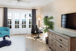 Habitación de hotel con cama, escritorio, silla, televisor, planta y vistas al exterior.