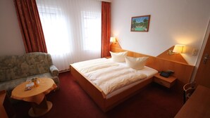 Een hotelkamer met een bed, een bureau, een stoel en een klein tafeltje.