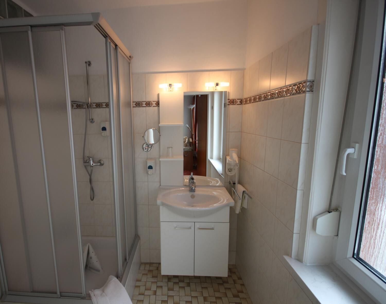A bathroom with a shower, sink, and mirror.