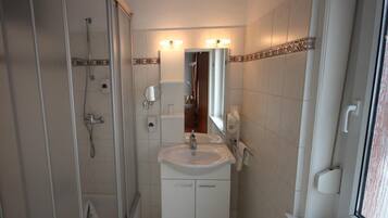 A bathroom with a shower, sink, and mirror.