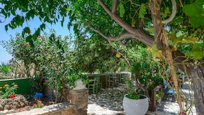 A stone-paved outdoor area with potted plants and a small seating area. - Studios Tasia (Naxos)