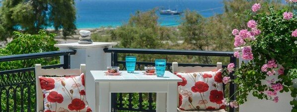 A balcony with a table, two chairs, and a view of the sea.