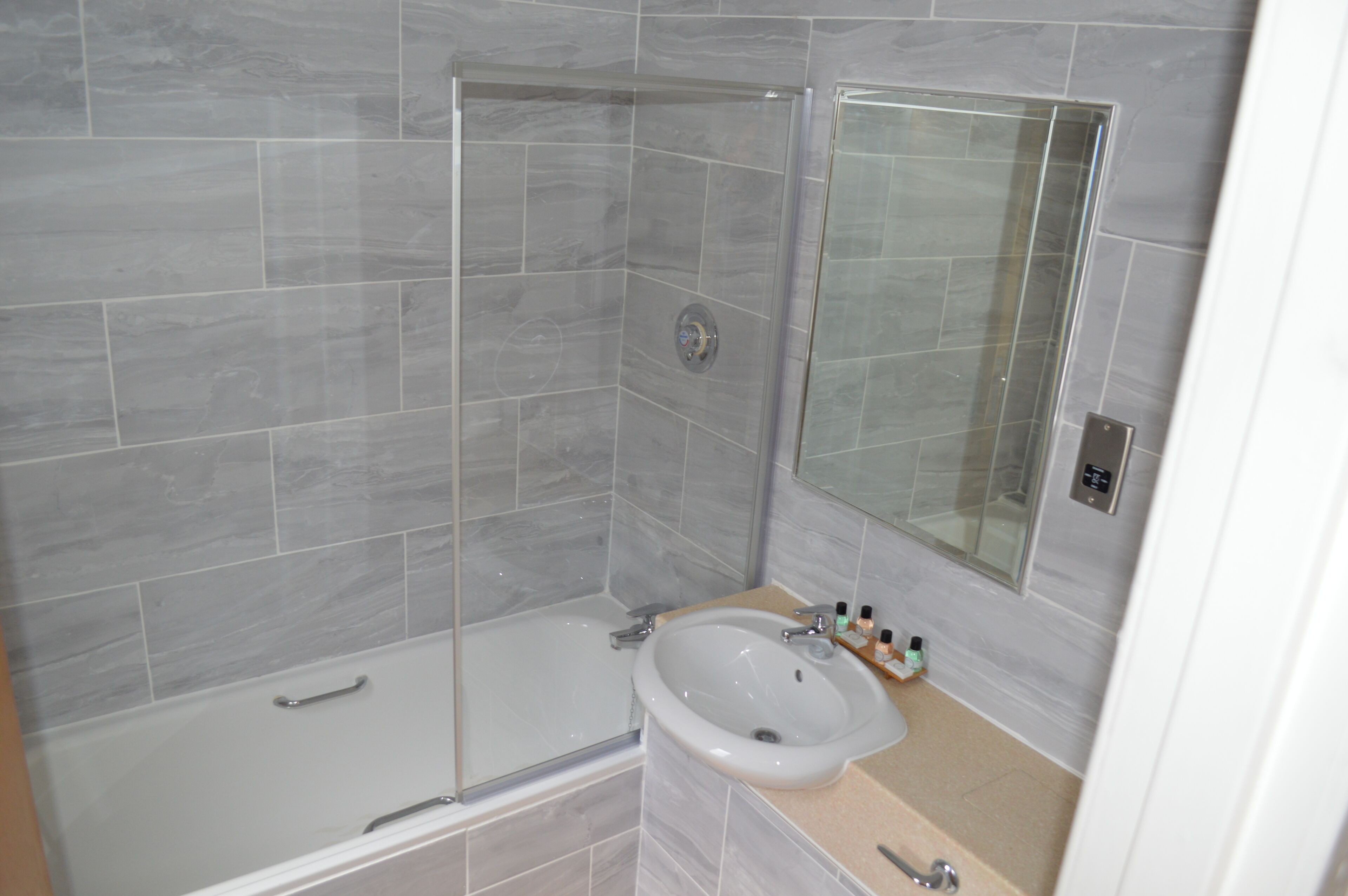 Un baño con ducha de vidrio, una bañera y un lavabo con espejo.