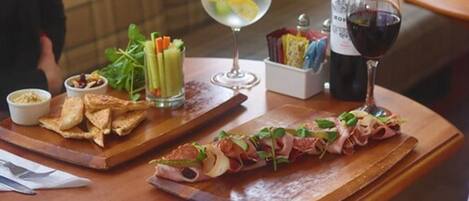 A table with a variety of food items, including a long piece of meat, a glass of red wine, and a glass of water with lemon slices.
