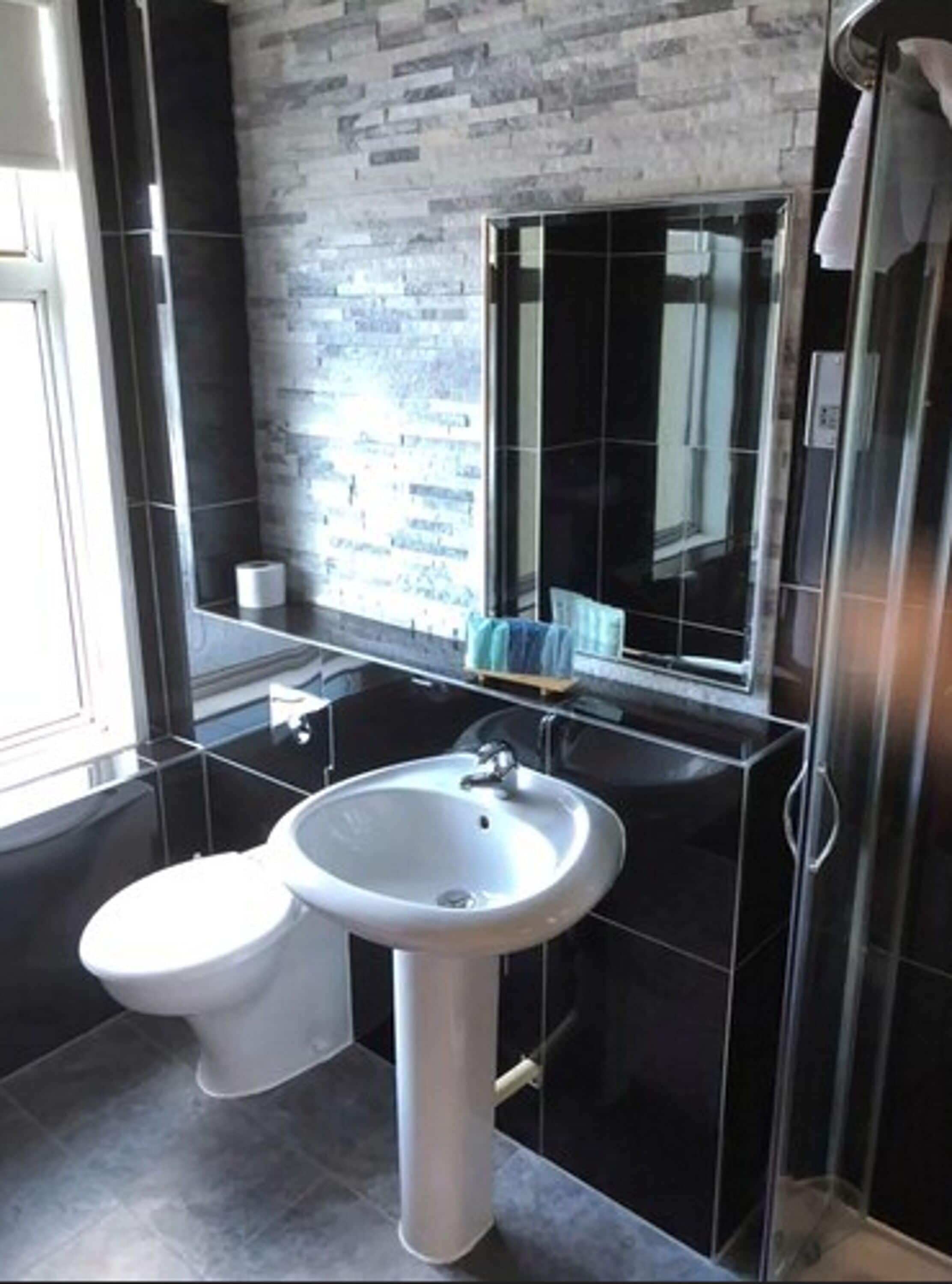Ein modernes Badezimmer mit Toilette, Waschbecken und einer Duschkabine aus Glas.