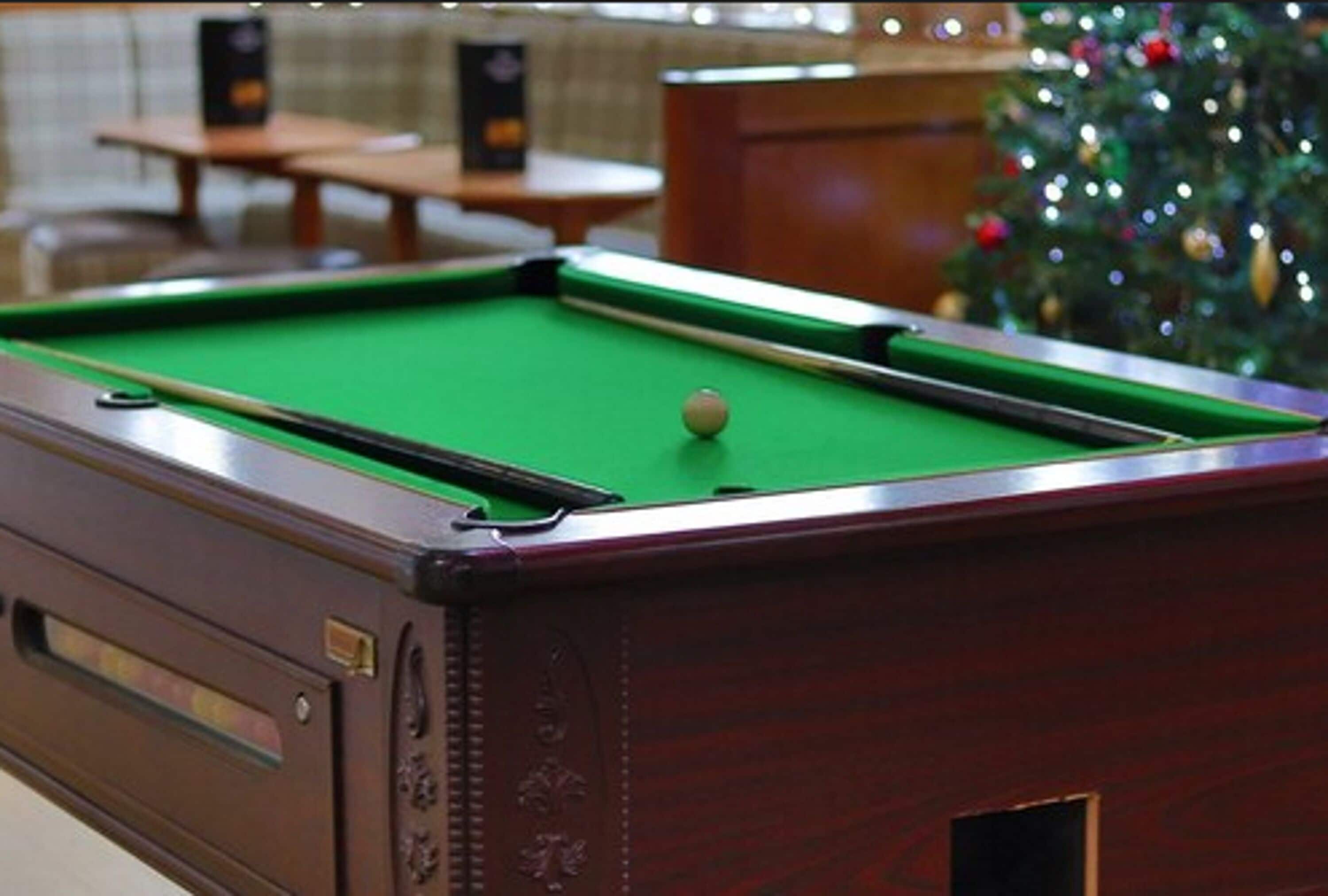 A pool table with a green felt surface and a cue ball.