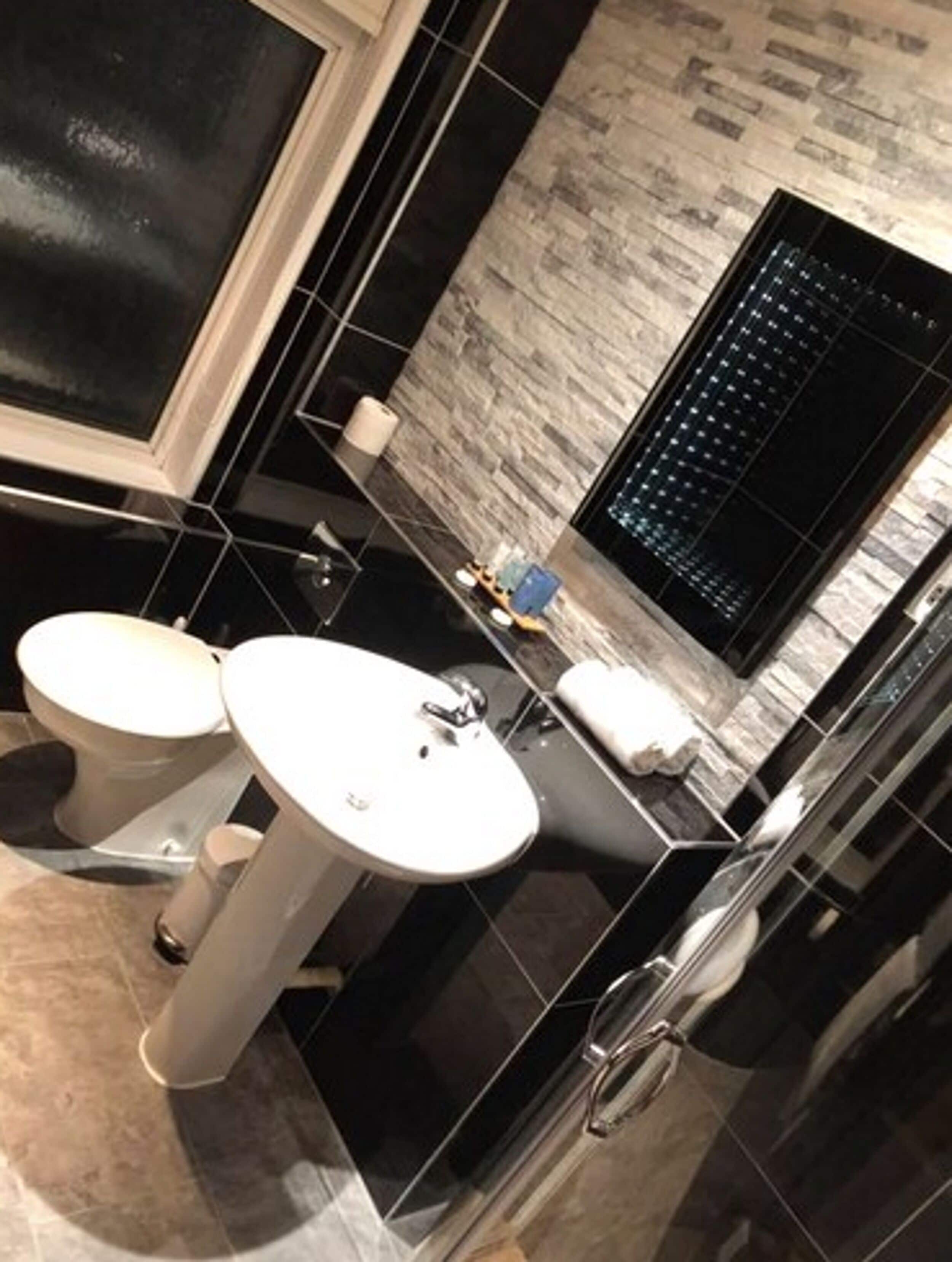 Une salle de bain moderne avec un sol carrelé en noir et blanc, un lavabo blanc et des toilettes.