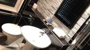 Une salle de bain moderne avec un sol carrelé en noir et blanc, un lavabo blanc et des toilettes.