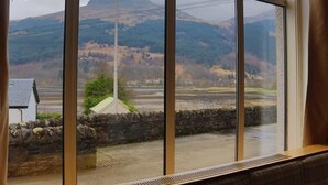 A room with large windows offering a view of a mountainous landscape. - Loch Long Hotel (Arrochar)