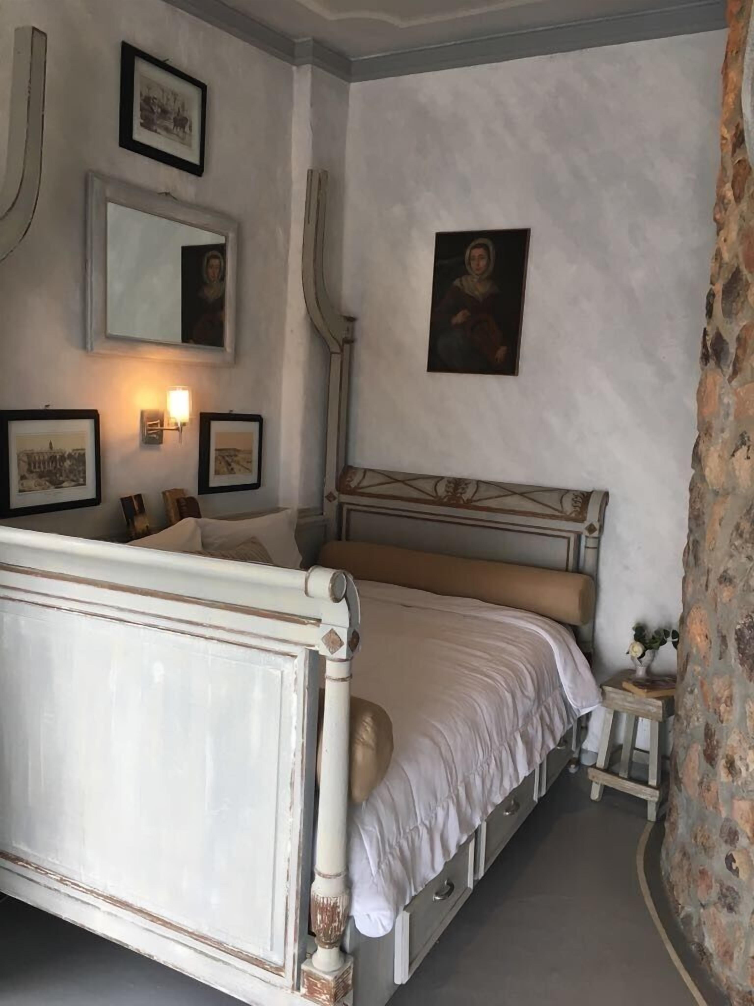 A bedroom with a bed, a nightstand, and a stone wall.