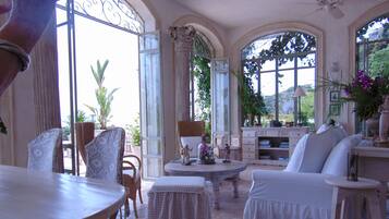 A spacious room with a large arched window, a dining table, and comfortable seating.